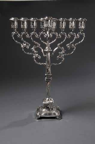 Chanukah lamp made of silver covered tin brass. Center of back panel incised in lattice pattern, edges in wavy incision. At center of back panel, link for shamash (missing).