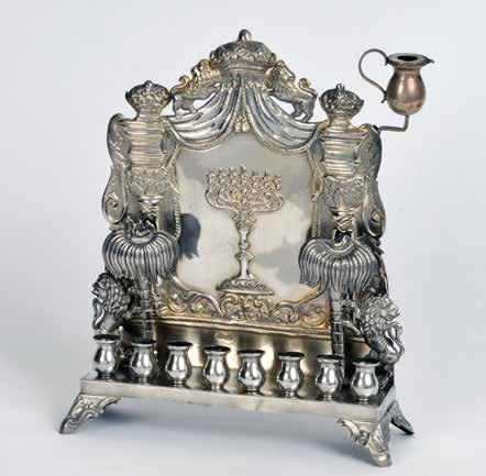 In front of the panel is a pair of free-standing lions holding palm trees (A bird in a nest is on every treetop). A Torah crown held by two lions is on the top of the lamp.