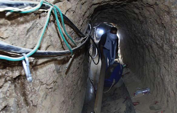 מבריח פלשתינאי במנהרה ברפיח בגבול מצרים-עזה. חמאס וקבוצות ג'יהאד אחרות ממשיכים להבריח טונות של רקטות, מרגמות וכלי נשק אחרים דרך מאות מנהרות דומות.