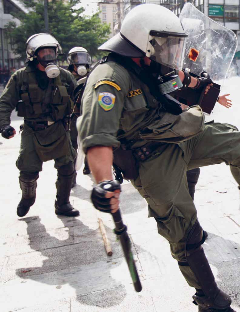 שוטר יווני מהמשטרה לפיזור הפגנות בועט במפגינה במהלך עימותים בכיכר סינטגמה, אתונה, 15 ביוני 2011.