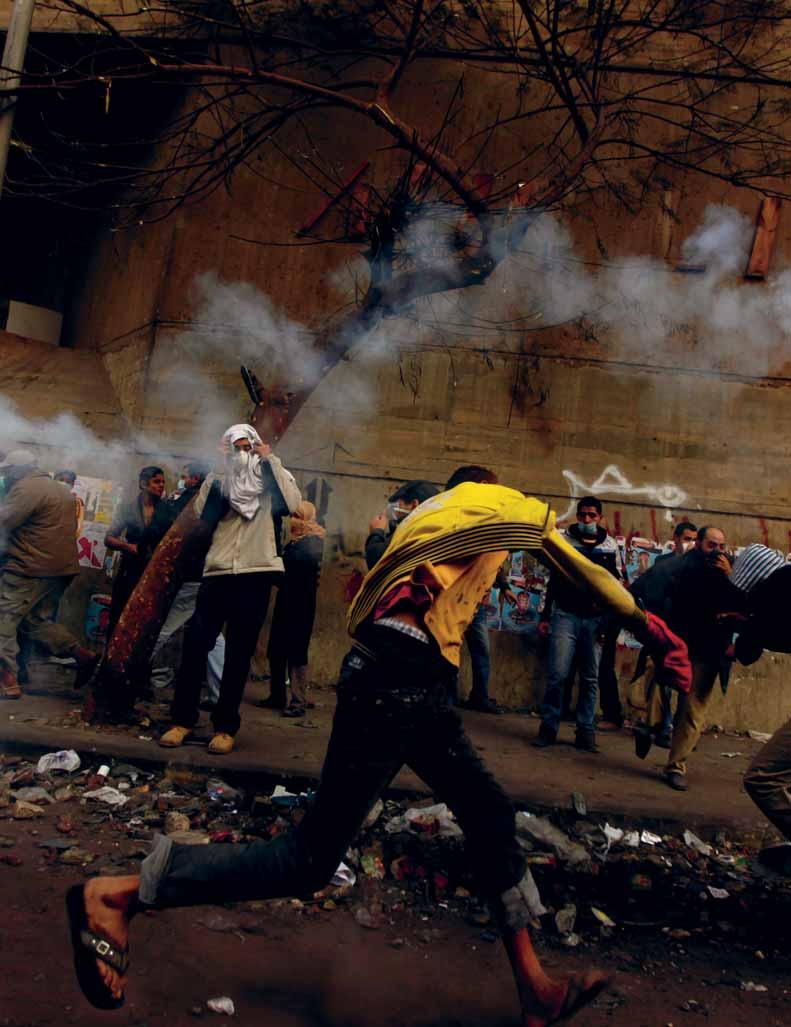 מפגין מרחיק מיכל גז מדמיע במהלך עימותים עם המשטרה המצרית לפיזור הפגנות בסמוך לכיכר תחריר בקהיר, 23 בנובמבר 2011.